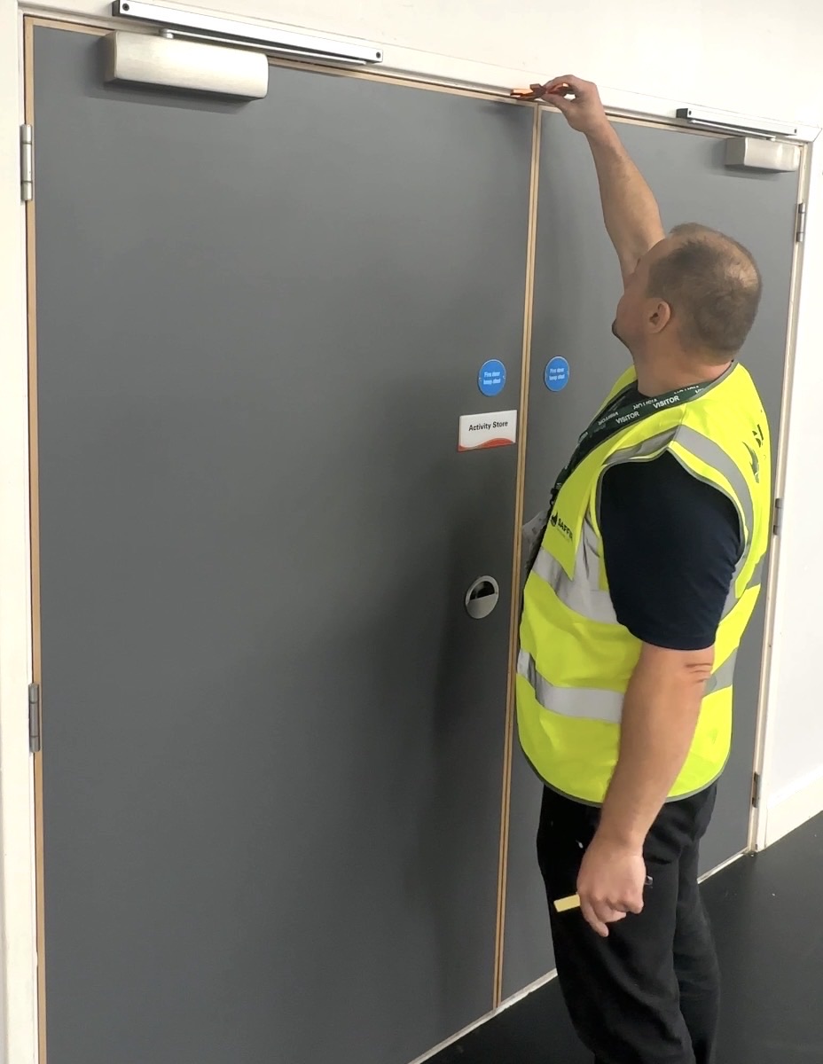 INTUMEX operative measuring the top gap of a double fire door set